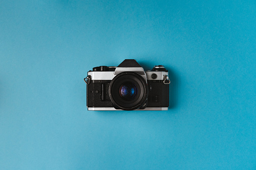 Comeback of film photography concept with vintage range finder analog camera on blue background,flat lay,negative space technique,free copy space