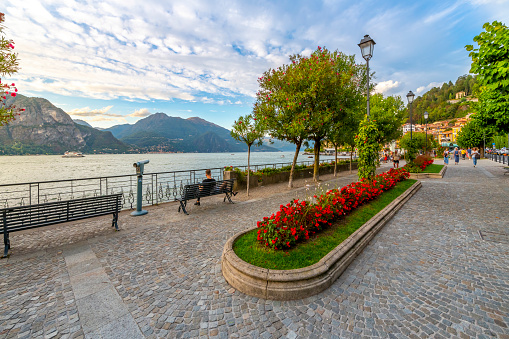 The lakefront promenade and park along the shores of Lake Como, at the Italian town of Bellagio, Italy, in the Northern Lombardy region. Bellagio is a village on a promontory jutting out into Lake Como, in Italy. It’s known for its cobbled lanes, elegant buildings and Villa Serbelloni Park, an 18th-century terraced garden with lake views.