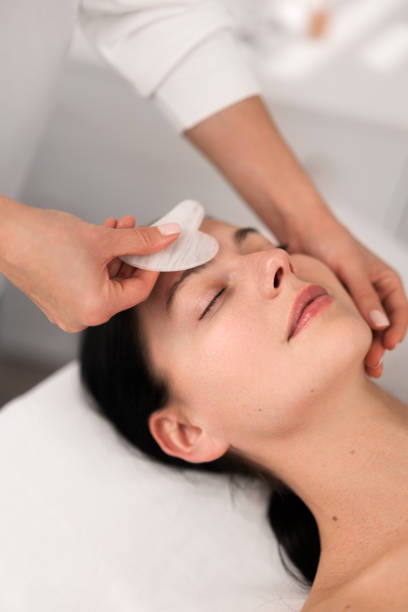 istock Crop beautician massaging forehead of client with gua sha 1481267684