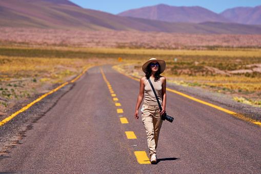 mid adult woman tourist photographer walking on the road on the altiplano in Los Flamencos National Reserve Antofagasta Region