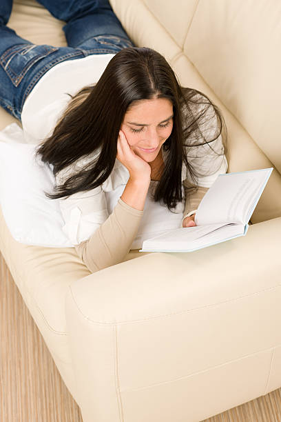 istock Attractive mid-aged woman read book on sofa 148127469