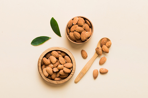 Fresh healthy Almond in bowl on colored table background. Top view.