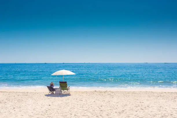 Photo of Women in sun hat on the beach enjoy summer seaside landscape. Blue ocean scenic view background. Holiday season sea travel. Sea relax tourist in busan at Haeundae beach.