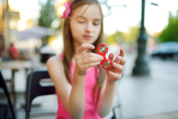 istock Cute school girl playing with colorful fidget spinner 1481285712