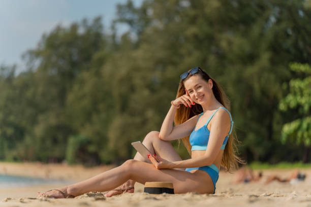 istock Digital nomad workcation at the beach. Beautiful caucasian woman in bikini using her digital tablet to work with her team and communicate with her friends happily on the beach 1481287845