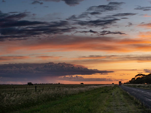 Truck driving into sunset Sunset storm clouds on country road in rural Victoria country road sky field cloudscape stock pictures, royalty-free photos & images