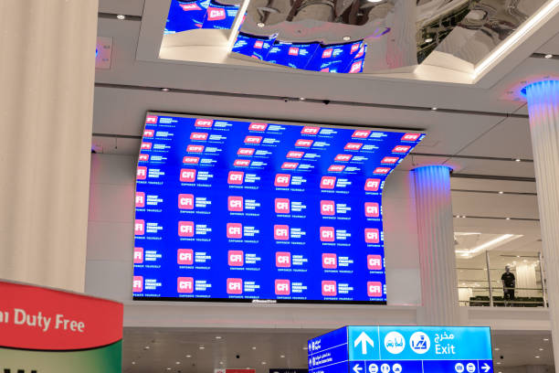 grande schermo pubblicitario nell'area ritiro bagagli dell'aeroporto internazionale di dubai nella città di dubai, emirati arabi uniti - dubai united arab emirates airport indoors foto e immagini stock