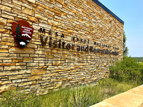 Montezuma County, Colorado - July 13, 2021: Bright sunlight bathes the entrance sign at the Mesa Verda National Park Visitor Center building in Southwest Colorado.
