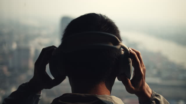 Man putting headphones on his head at rooftop terrace ,Slow motion