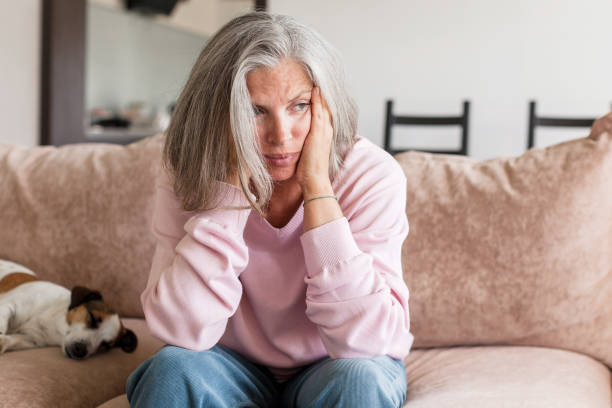 istock Sad pensive middle age woman looking down depressed sitting on the sofa 1481305558