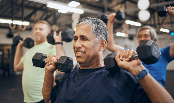 istock Training, group and senior men exercise together at the gym lifting weights with dumbbells equipment for strength. Elderly, old and fitness people workout in a sports club for wellness and health 1481305585