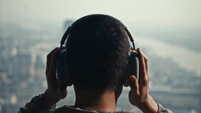 Man putting headphones on his head at rooftop terrace ,Slow motion