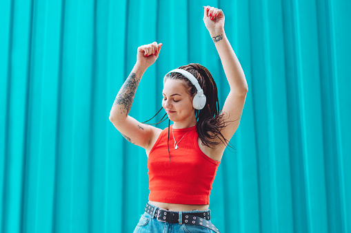 Young woman listening to music and dancing using mobile and headphones