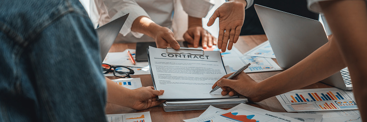Panorama shot hand signing signature on legal contract, business report and BI Fintech paper on table. Seal business agreement deal with signature. Investment loan for startup company. Scrutinize