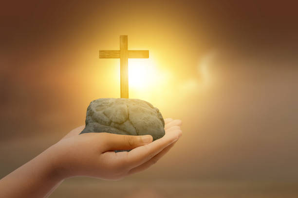 A white cross on top of a huge rock under the blue sky and the moon in the sky