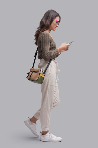 Young casual woman standing and chatting with her smartphone, communication and technology concept
