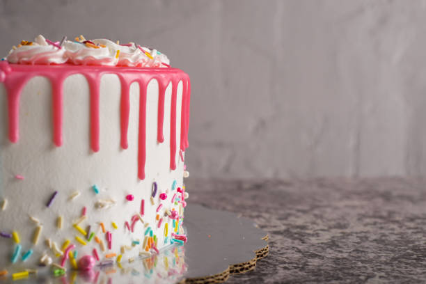 istock Very colorful cake decorated with pink icing on a cement table. 1481317253