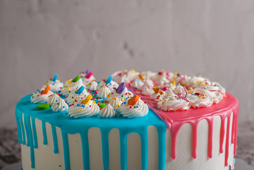 Very colorful cake decorated with blue and pink icing on a cement table.