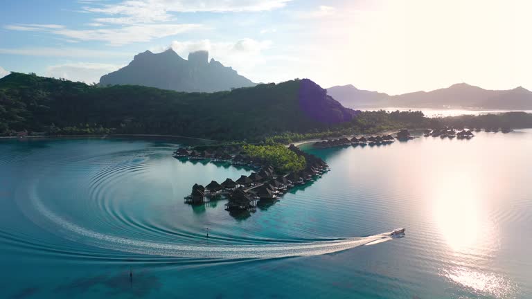 Luxury travel vacation aerial of overwater bungalows resort in coral reef lagoon ocean by beach. Aerial Drone video at sunset paradise getaway Bora Bora, French Polynesia, Tahiti, South Pacific Ocean