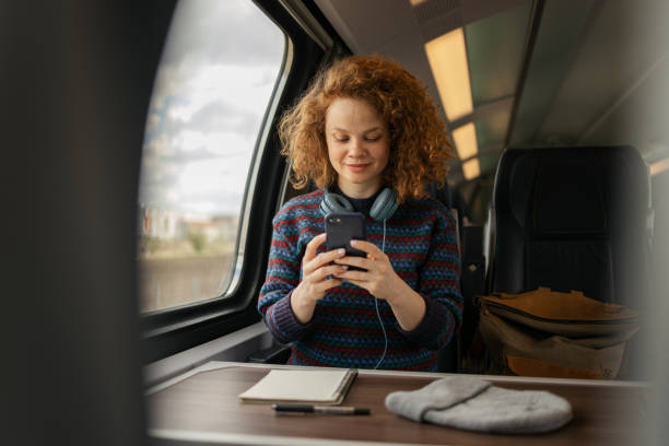 istock Redhead woman using mobile phone while traveling by train. 1481318535