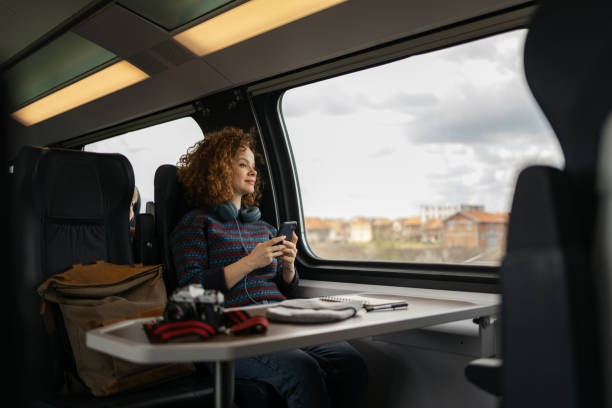 Smiling woman day dreaming while using cell phone in a train.