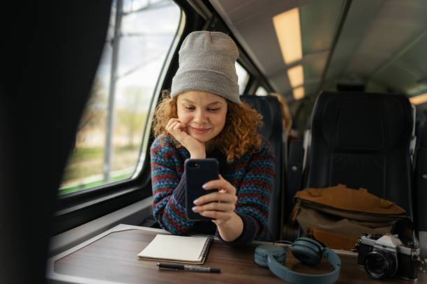 istock Smiling redhead woman using smart phone while traveling by train. 1481319124