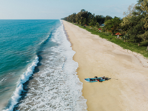 A small group of thai fishermen pushing a typical thai longtail boat towards the sea to go for fishing. Thailand Beach at the Andaman Sea Coast., Thai Mueang under blue summer sky. Drone Point of View along Thai Mueang Beach and Scene - Phang Nga Bay Coast.  Western Coast of Thailand, Khok Kloi, Phang Nga, Northern Phuket, Andaman Sea, Thailand, Southeast Asia