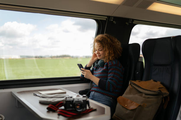 istock Smiling redhead woman using smart phone while traveling by train. 1481320616