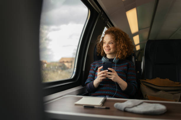 istock Happy redhead woman using mobile phone while day dreaming during her trip by train. 1481320636