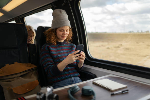 istock Smiling female tourist using smart phone while traveling by train. 1481320655