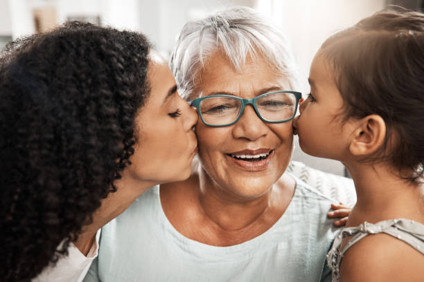 bacio, affetto e figli con la nonna per amore, compleanno o festa della mamma. gratitudine, cura e una donna anziana con un bambino e una figlia che si baciano per apprezzamento, cura e amore a casa - mothers day mother kissing child foto e immagini stock