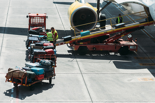 Bilbao, Spain - April 9, 2023: Workers placing luggage in trailer to load an airplane at Bilbao Airport