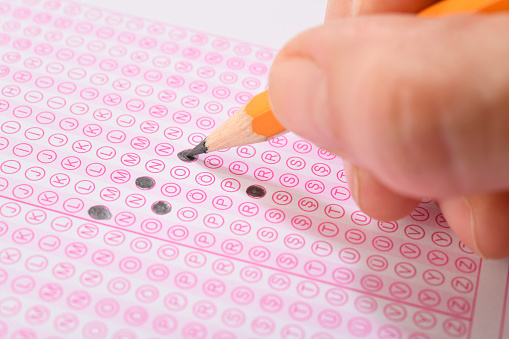 Student filling out answers to a test with orange pencil close-up