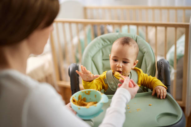 istock Mother spoon feeding her baby son at home 1481334028