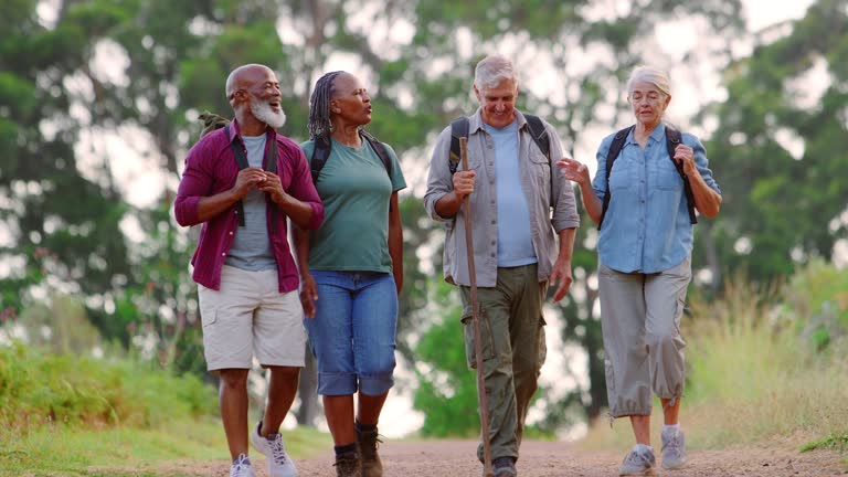 Group Of Active Senior Friends Enjoying Hiking Through Countryside Walking Along Track Together