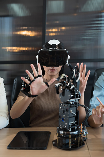 Young female wearing vr glasses control AI robot arm system in workshop. Female working and training Programmable logic controller robotics arm system project