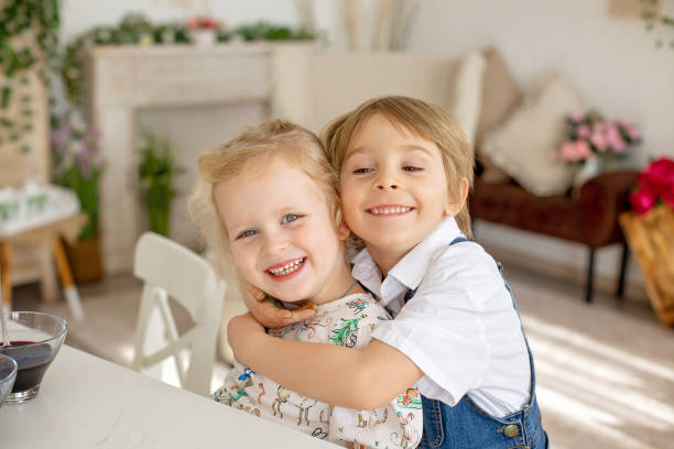istock Happy children, siblings, coloring eggs for Easter at home, sunny room 1481336100