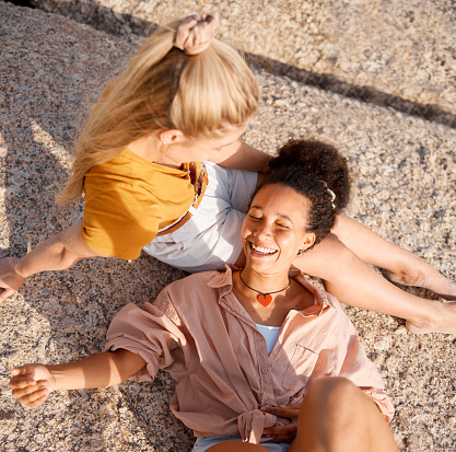 Above, friends and relax at the beach for summer, vacation and bonding while lying on the ground together, happy and laugh. Smile, travel and women on floor with peace, freedom and chilling outdoors