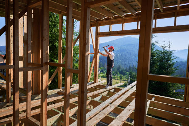 istock Carpenter hammering nail while constructing wooden frame two-story house near the forest. 1481338793