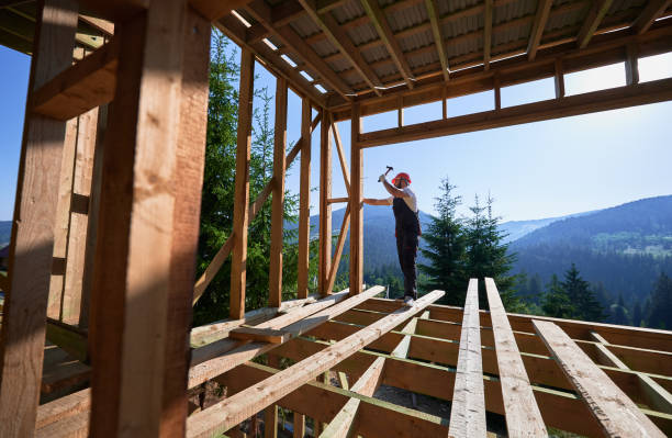 istock Carpenter hammering nail while constructing wooden frame two-story house near the forest. 1481338804