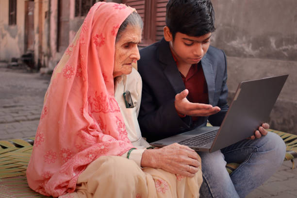 Grandson using laptop with his Grandmother stock photo