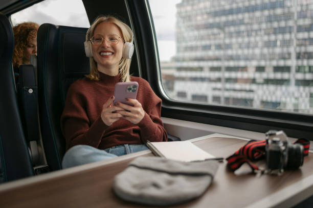 istock Happy female tourist using mobile phone while listening music in a train. 1481340561
