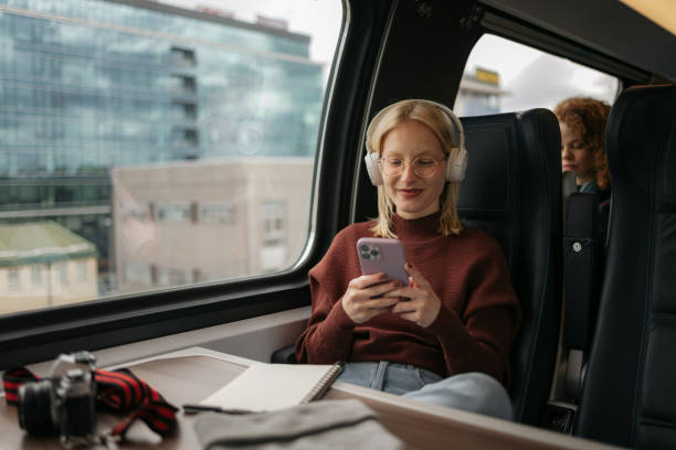 istock Smiling female tourist using cell phone while listening music in a train. 1481341547