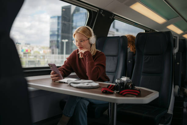 istock Smiling woman using smart phone while listening music in a train. 1481341608