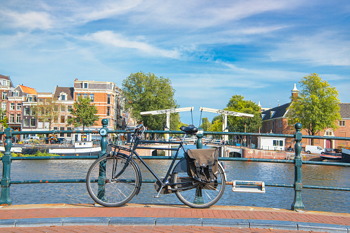Delft, The Netherlands - October 10, 2019: Over the canal is a small bridge with white railings. It is here that several bicycles have been parked. Delft is a popular tourist destination. Many tourists come here and find in this city a summary of the architecture, art and landscape of the Netherlands. Many historical buildings have been preserved in the old part of the city. There are many narrow streets and many of them are canals, the banks of which are connected by small bridges. The city is known for its connections to art, culture and science.
