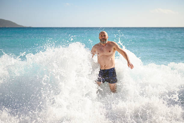 mature adult man swimming in the sea mature adult man swimming in the sea spume stock pictures, royalty-free photos & images