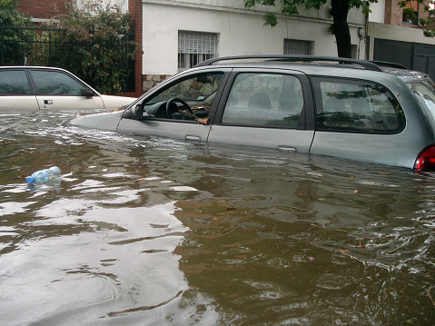 Aftermath of severe flooding that occurred in Buenos Aires, Argentina in 2006. The floodwaters have partially submerged buildings and cars, leaving debris and muddy water throughout the affected areas.