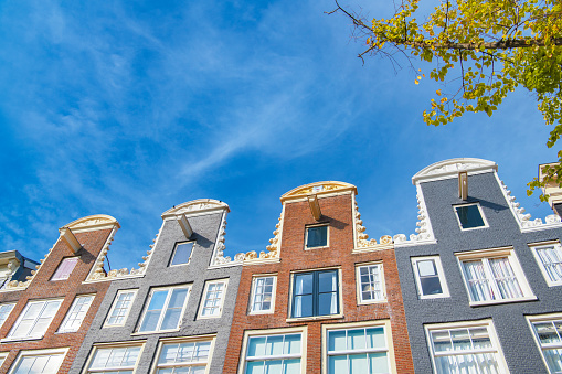 Amsterdam canal house facades with a blue sky in the background during summer.