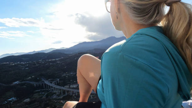 istock Mature female hiker relaxes at summit viewpoint above distant mountains 1481349303
