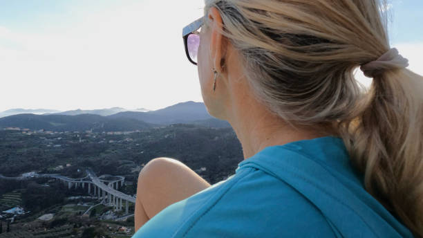 istock Mature female hiker relaxes at summit viewpoint above distant mountains 1481349675